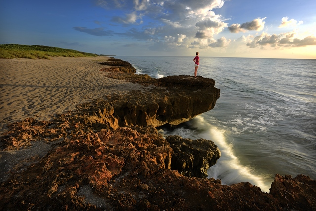 woman standing on cliff by ocean